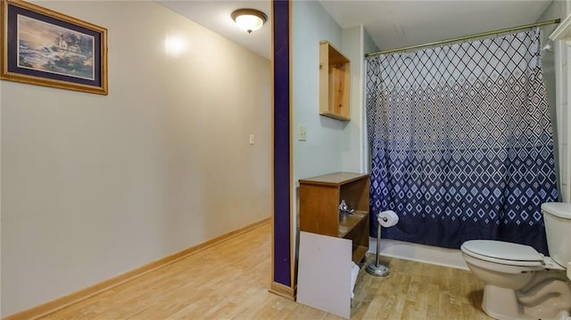 bathroom with toilet, a shower with curtain, and wood finished floors