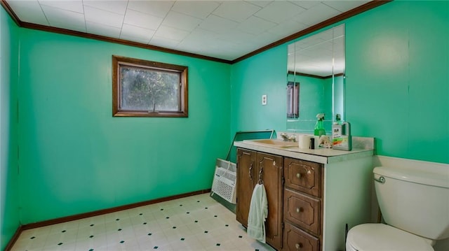 bathroom with tile patterned floors, toilet, crown molding, baseboards, and vanity