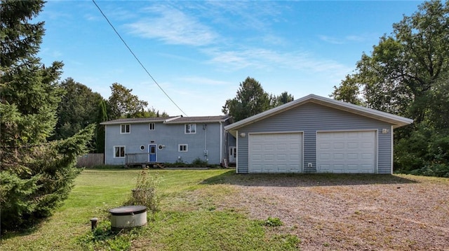 rear view of property with an outdoor structure, a lawn, and a garage