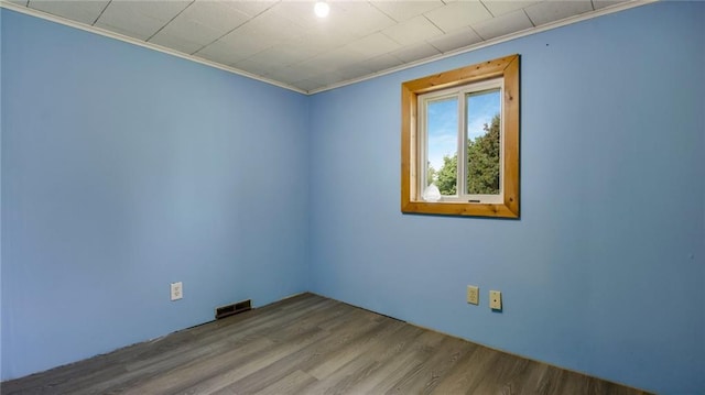 empty room featuring visible vents, crown molding, and wood finished floors