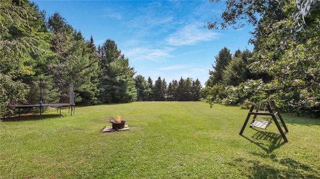 view of yard featuring a trampoline and an outdoor fire pit