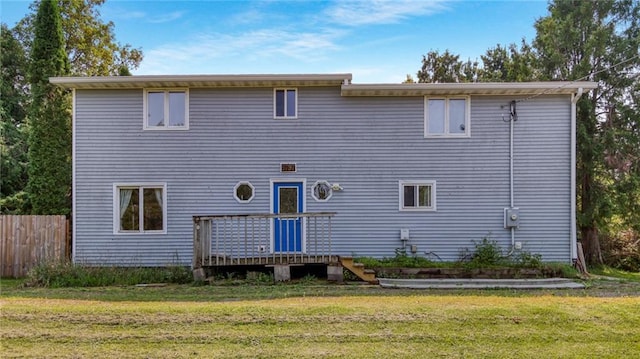 back of property with a lawn, fence, and a wooden deck