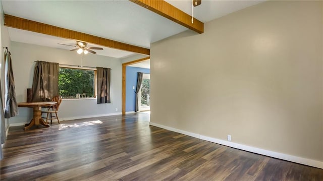 spare room featuring beamed ceiling, wood finished floors, baseboards, and ceiling fan