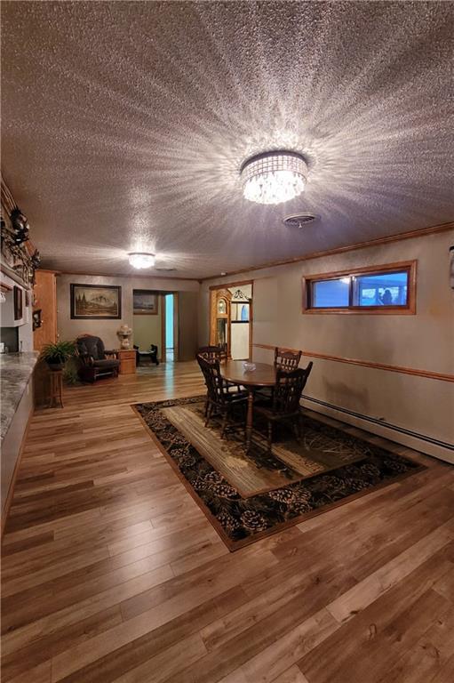 corridor with hardwood / wood-style floors, a textured ceiling, and ornamental molding