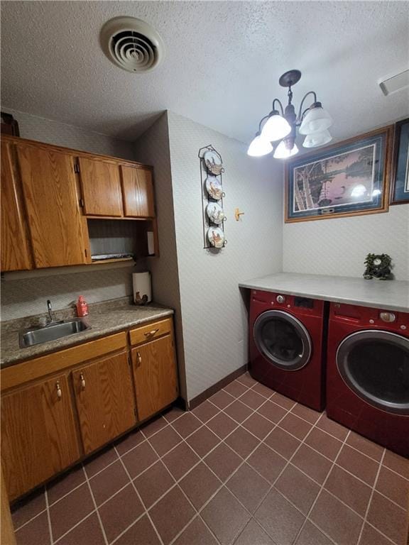 interior space featuring a textured ceiling, cabinets, independent washer and dryer, sink, and a chandelier