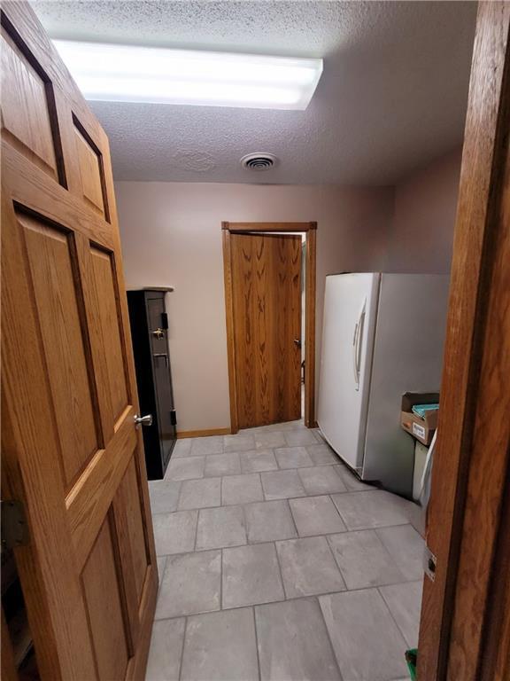 interior space with a textured ceiling, washer / dryer, ornamental molding, and light wood-type flooring