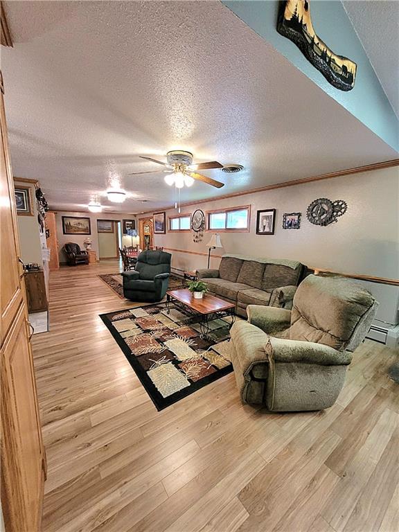 living room featuring a textured ceiling, ceiling fan, and light hardwood / wood-style floors