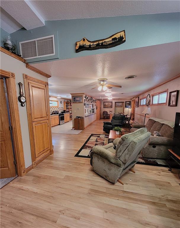 living room featuring ceiling fan, light hardwood / wood-style floors, a textured ceiling, and vaulted ceiling