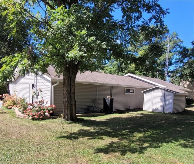 view of home's exterior with a storage unit and a lawn