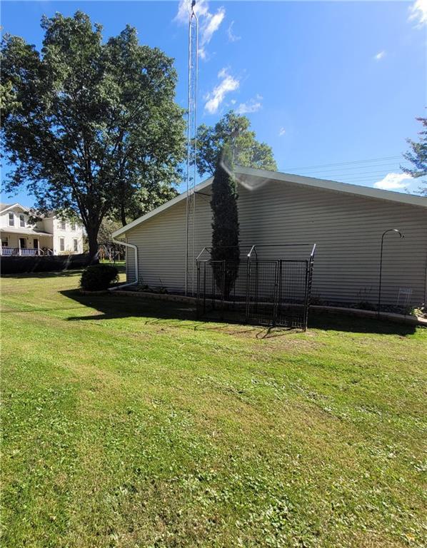 view of front of property featuring cooling unit, an outbuilding, a garage, and a front lawn