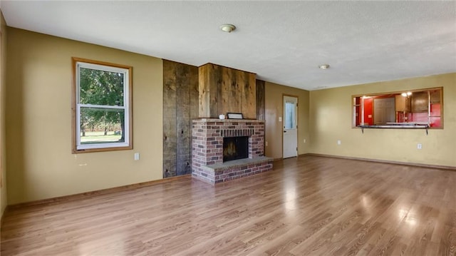 unfurnished living room with a textured ceiling, a brick fireplace, and hardwood / wood-style floors