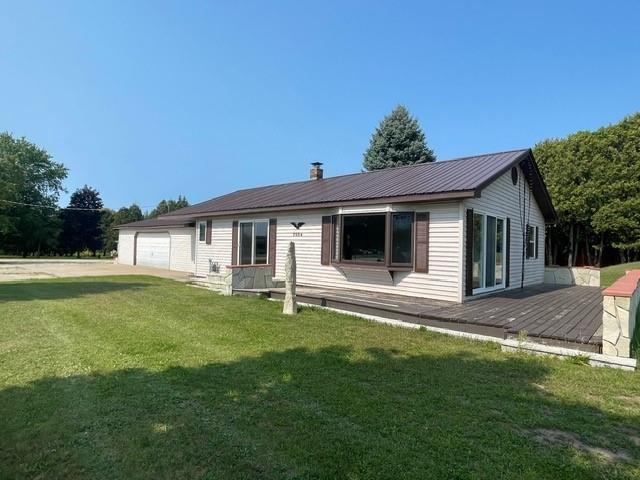 back of house featuring a yard, a wooden deck, and a garage