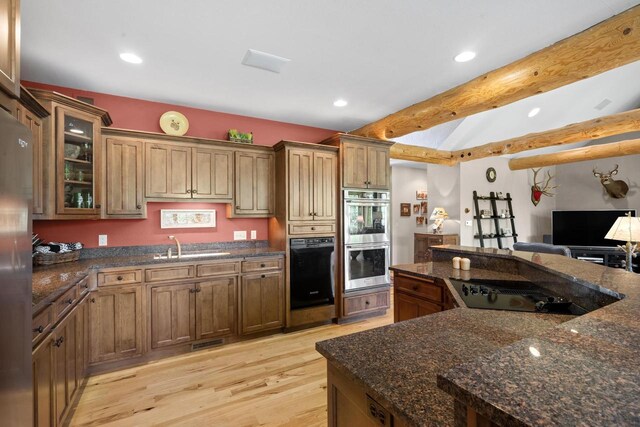 kitchen with glass insert cabinets, dark stone countertops, double oven, and light wood-type flooring