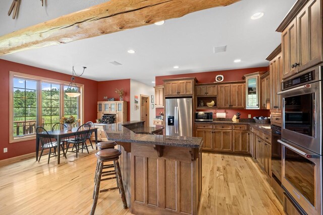 kitchen featuring a kitchen bar, recessed lighting, light wood-type flooring, and appliances with stainless steel finishes