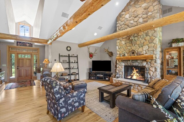 living room with a fireplace, beam ceiling, wood finished floors, and a wealth of natural light