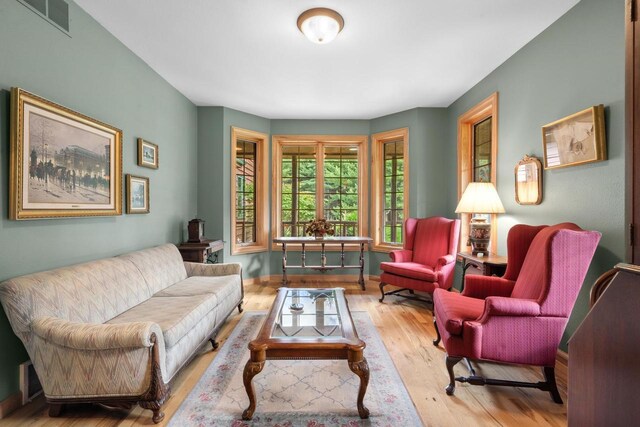 living room featuring visible vents, baseboards, and wood finished floors