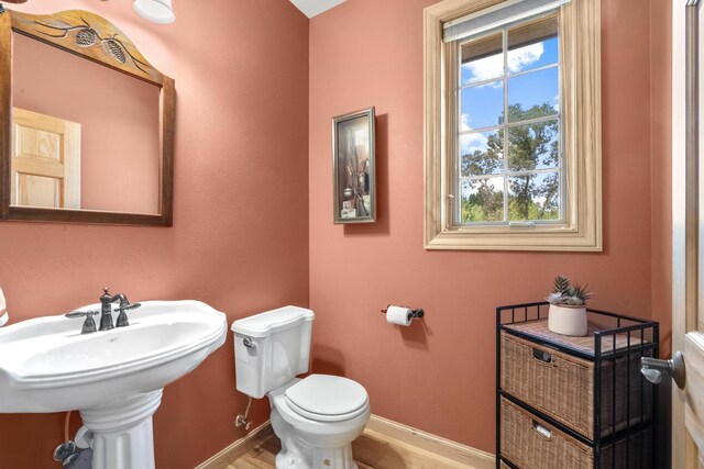 bathroom with toilet, baseboards, and wood finished floors