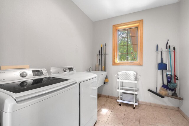 clothes washing area with laundry area, light tile patterned flooring, washing machine and dryer, and baseboards