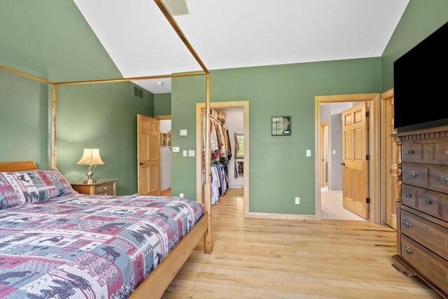 bedroom with light wood-type flooring, visible vents, a closet, baseboards, and a spacious closet