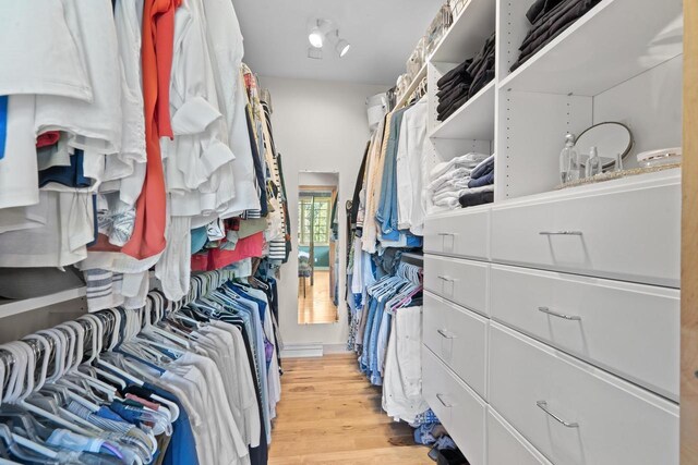 walk in closet with light wood-style floors