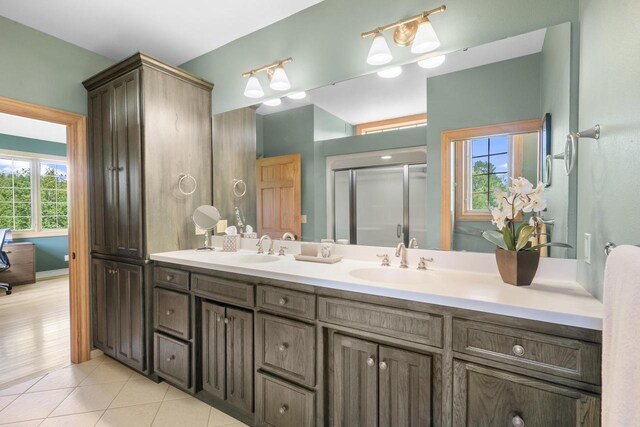 full bathroom featuring tile patterned floors, double vanity, a stall shower, and a sink