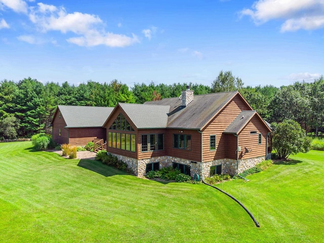 back of house featuring a yard, central air condition unit, a chimney, and a shingled roof