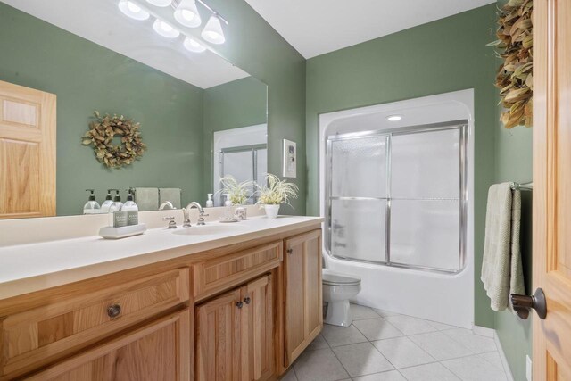 bathroom featuring tile patterned floors, enclosed tub / shower combo, toilet, and vanity