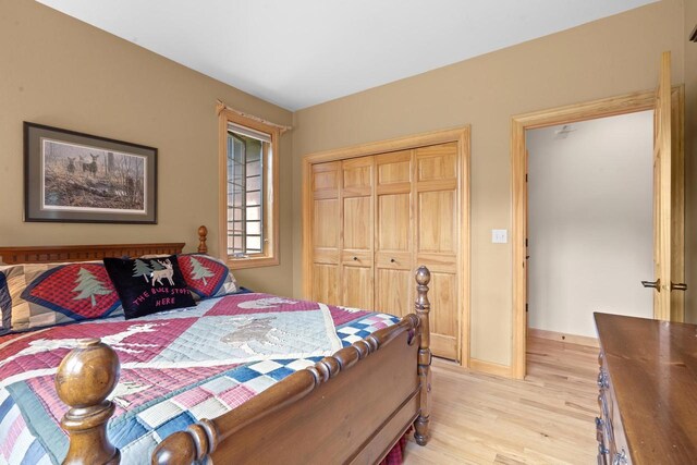 bedroom with light wood finished floors, baseboards, and a closet