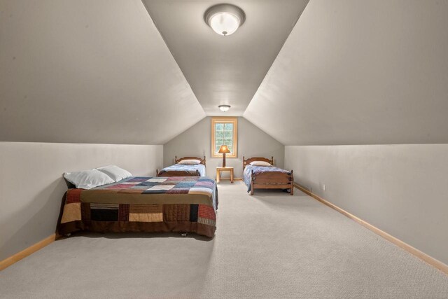 carpeted bedroom with lofted ceiling and baseboards