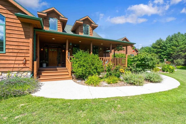 entrance to property with a porch and a lawn