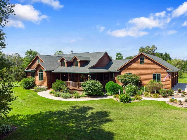 log home featuring covered porch and a front yard