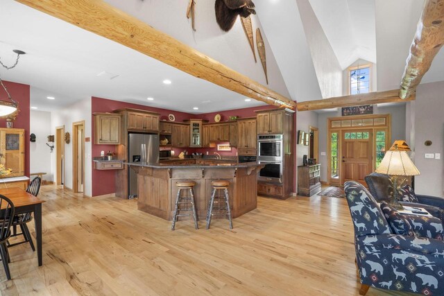 kitchen featuring glass insert cabinets, appliances with stainless steel finishes, a breakfast bar area, and light wood finished floors