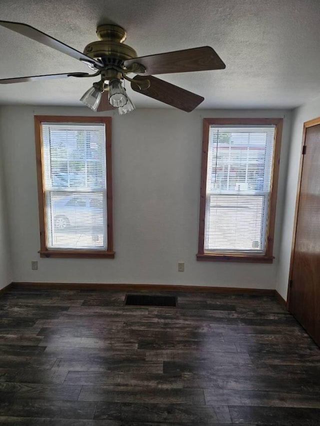 spare room with a wealth of natural light, a textured ceiling, and wood finished floors