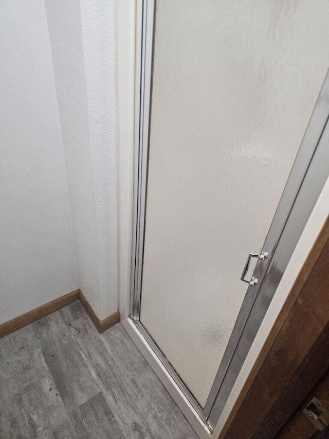 bathroom featuring a stall shower, baseboards, and wood finished floors