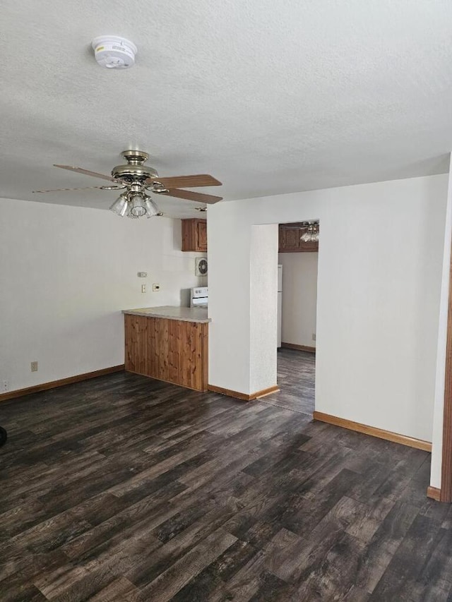 unfurnished living room with ceiling fan, baseboards, dark wood-style flooring, and a textured ceiling