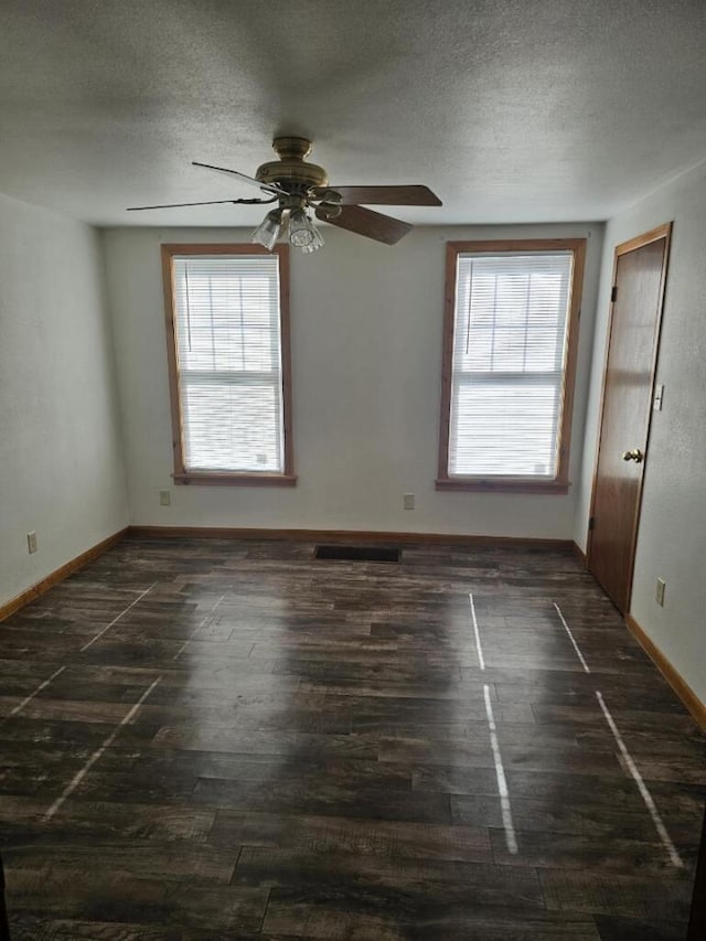 unfurnished room featuring dark wood-style flooring, a wealth of natural light, and a textured ceiling