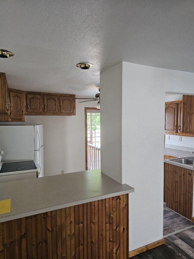 kitchen with a ceiling fan, a sink, a textured ceiling, dark wood finished floors, and freestanding refrigerator