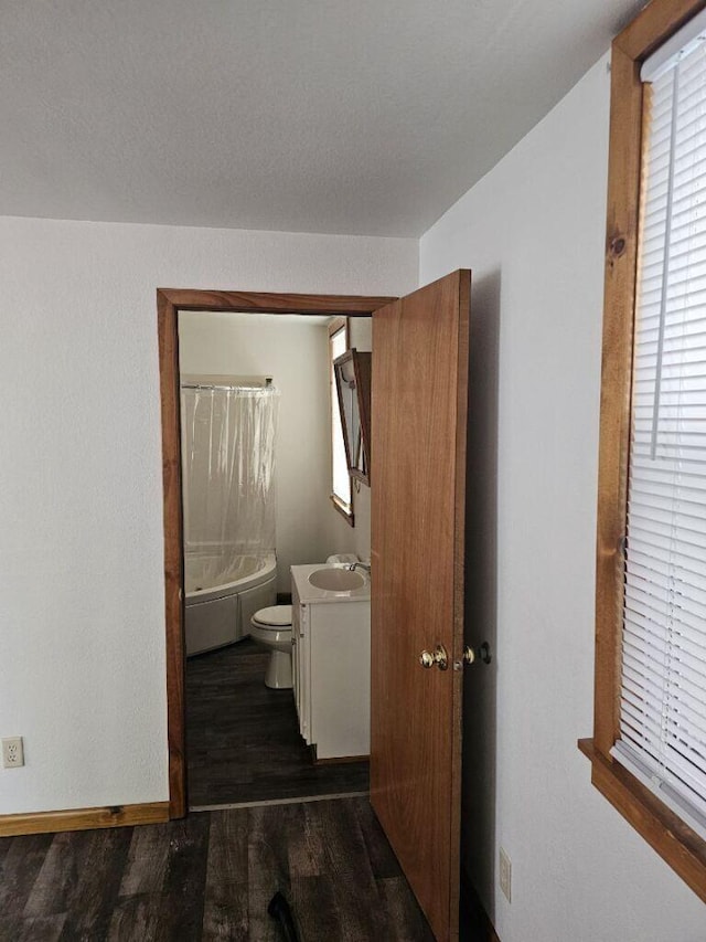 bathroom featuring vanity, wood finished floors, baseboards, shower / bath combo, and toilet