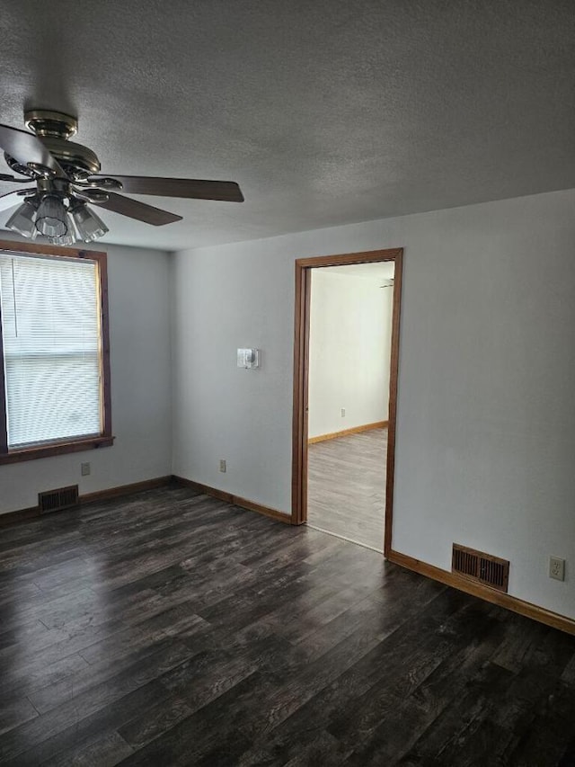 empty room with baseboards, wood finished floors, visible vents, and a textured ceiling