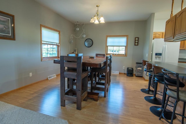 dining room featuring a wealth of natural light, an inviting chandelier, and light hardwood / wood-style flooring