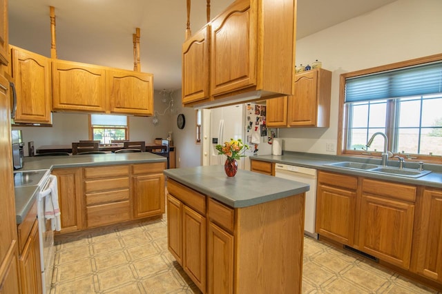 kitchen with a wealth of natural light, a kitchen island, sink, and white appliances