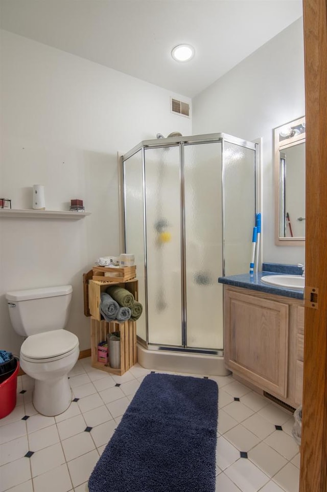 bathroom featuring tile patterned flooring, toilet, a shower with door, and vanity