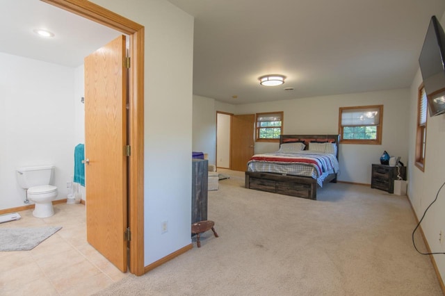 bedroom with ensuite bath and light carpet