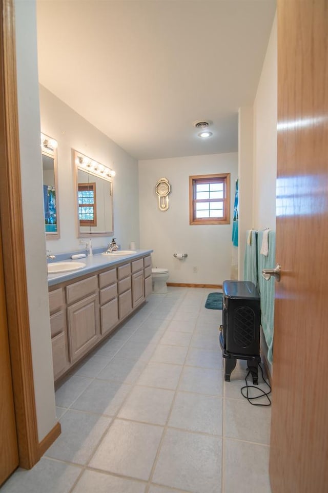 bathroom featuring tile patterned flooring, toilet, a wood stove, and vanity