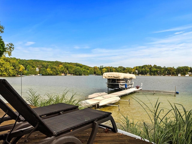 view of dock featuring a wooded view and a water view