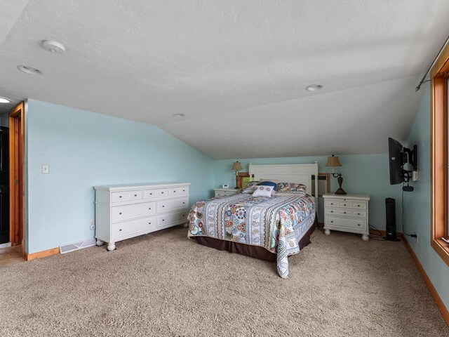 bedroom with lofted ceiling, baseboards, visible vents, and a textured ceiling