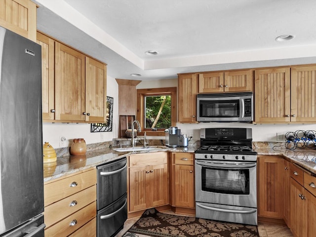 kitchen with light stone counters, light tile patterned floors, appliances with stainless steel finishes, and a sink