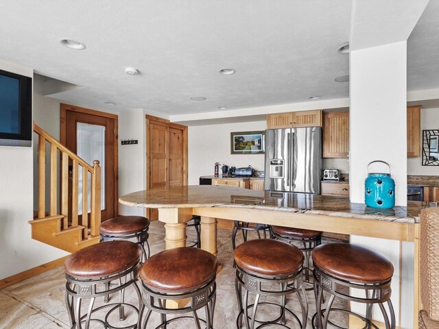 kitchen featuring a kitchen breakfast bar, kitchen peninsula, and stainless steel fridge with ice dispenser