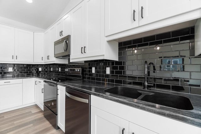 kitchen with decorative backsplash, appliances with stainless steel finishes, white cabinets, and light hardwood / wood-style floors