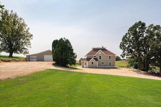 view of front of property featuring a garage, a front lawn, and an outbuilding